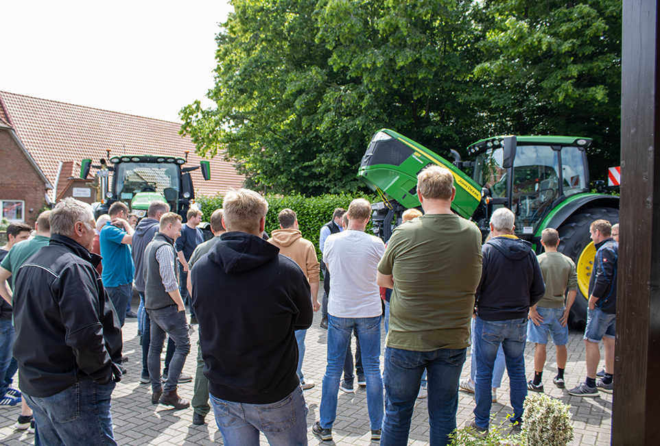 Viele Menschen, die sich 2 Traktoren anschauen an denen von einem Schulungsleiter etwas erklärt wird
